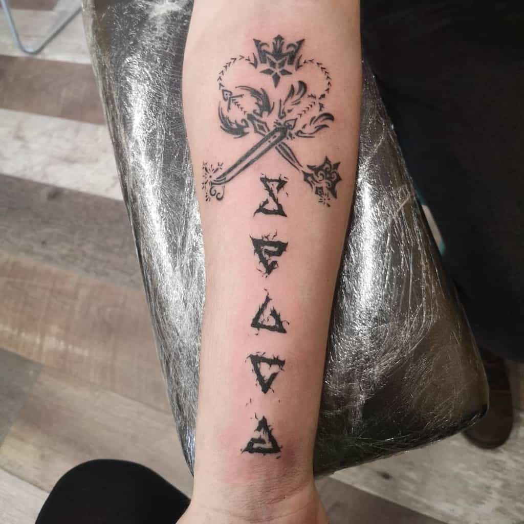 Kingdom Hearts-inspired forearm tattoo featuring a Keyblade with ornate details and a vertical line of stylized lettering below it.