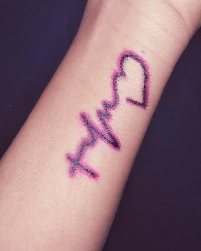 Forearm tattoo featuring a bold cross, heartbeat line, and heart symbol with a pink outline for added emphasis