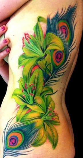 Vibrant side tattoo featuring large green lilies intertwined with detailed peacock feathers, showcasing bright colors and intricate shading.
