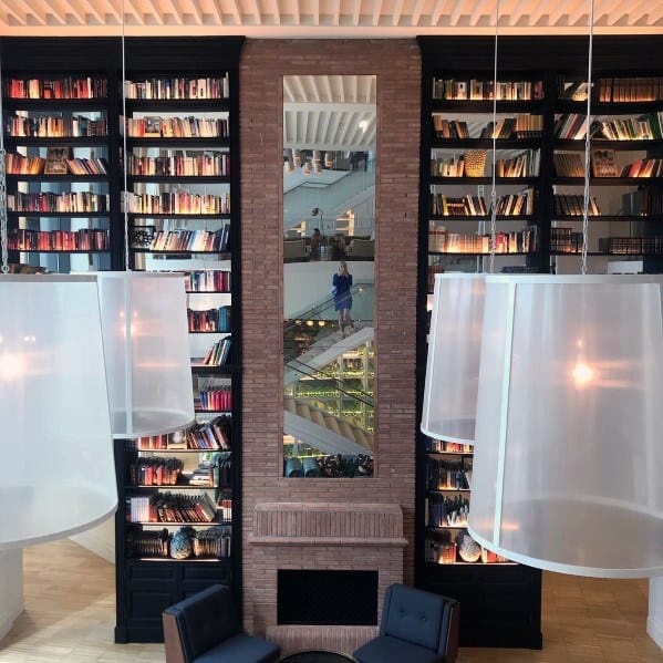 A bookshelf wall with mirrored panels, featuring oversized pendant lights