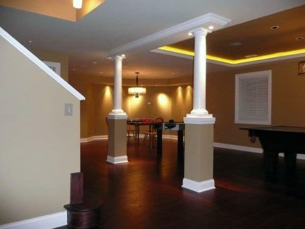 basement with tan walls, white decorative columns, and warm recessed lighting.