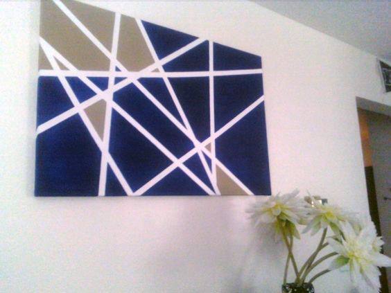 Abstract blue and white geometric canvas art with tan accents on a white wall.