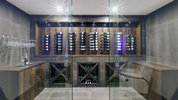 Modern wine cellar with glass walls, dark wood racks, and spot lighting showcasing exquisite wine bottles