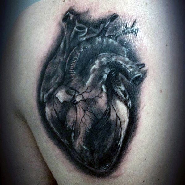 Black and grey 3D tattoo of an anatomical heart with cracked textures and deep shading, creating a bold and dramatic effect on the shoulder.