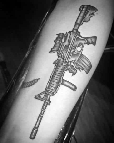Black and grey AR-15 tattoo on the forearm, featuring intricate shading and a battle-worn design, symbolizing strength, resilience, and tactical readiness.