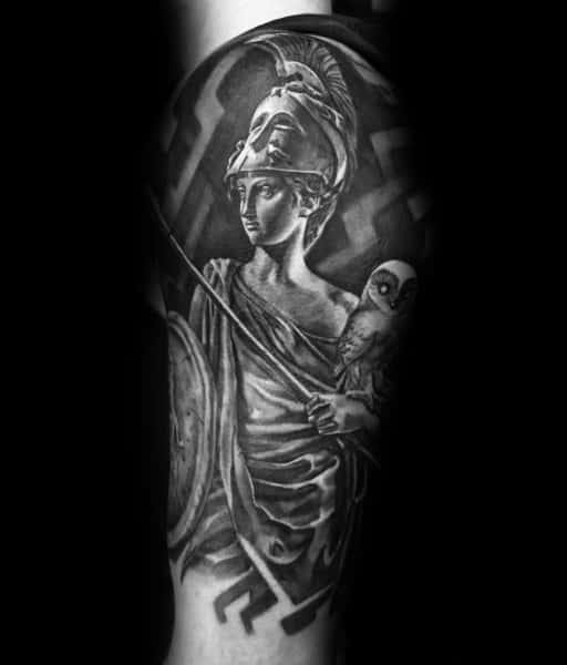 Athena tattoo in classical black and grey realism with spear, shield, draped robe, and a perched owl on her arm against a patterned backdrop