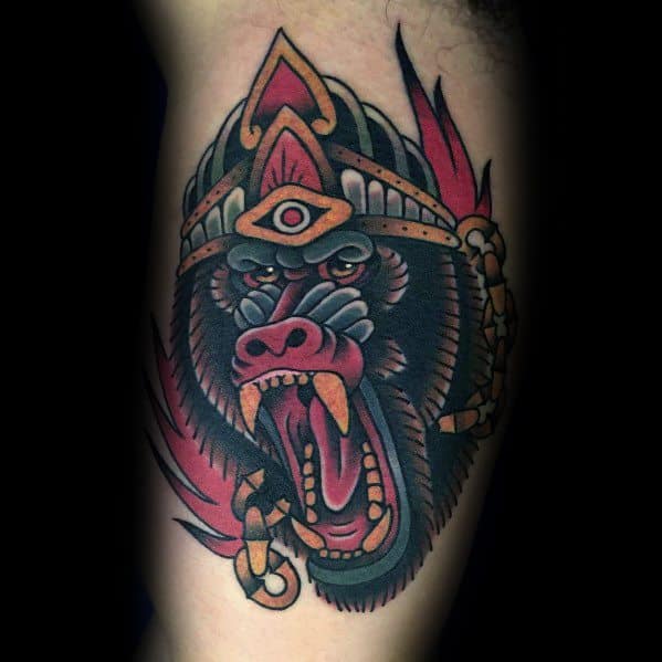 Neo-traditional baboon tattoo with bold colors, fierce expression, and tribal-inspired headdress, featuring a third eye for a mystical and powerful design.
