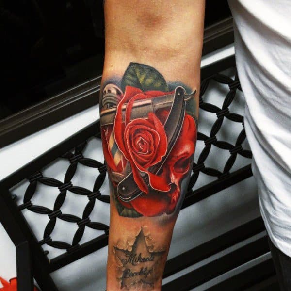Forearm tattoo of a red rose with a razor, leaf, and metallic background designs