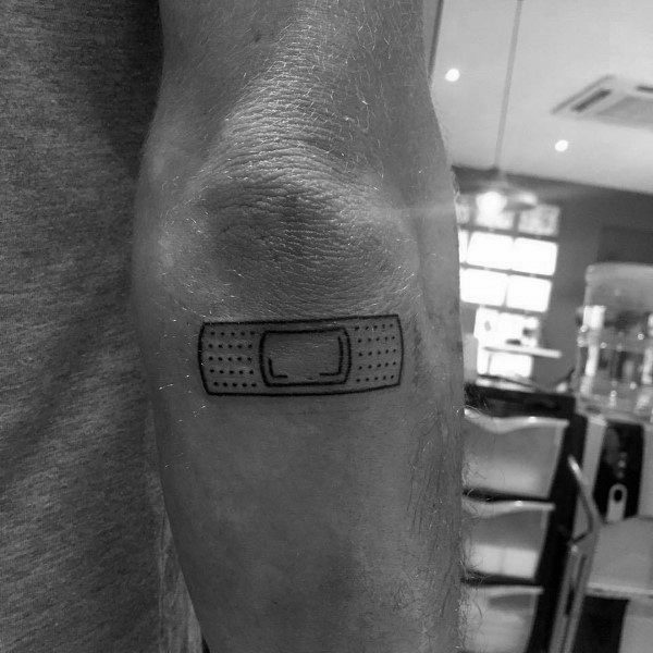 Simple Band-Aid tattoo outlined in black with minimal dot detail, placed on the elbow for a clean and symbolic look.