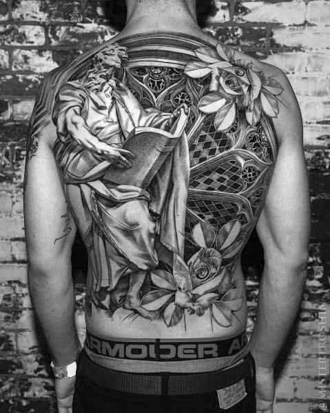 Black and grey full-back tattoo featuring a highly detailed statue-like figure reading a book, surrounded by roses, stained glass, and intricate shading.