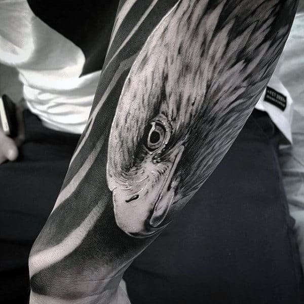Black and white tattoo of an eagle's head on a person's forearm