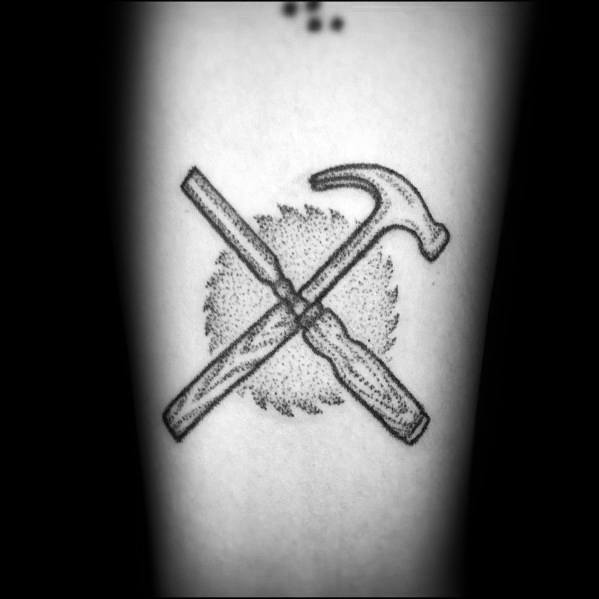 Dotwork-style tattoo of a crossed hammer and chisel over a saw blade, symbolizing craftsmanship, woodworking, and dedication to the trade.
