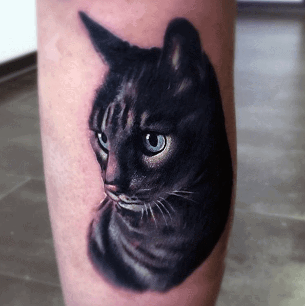 Hyper-realistic black cat tattoo with striking blue eyes, featuring detailed fur shading for a lifelike and captivating design.