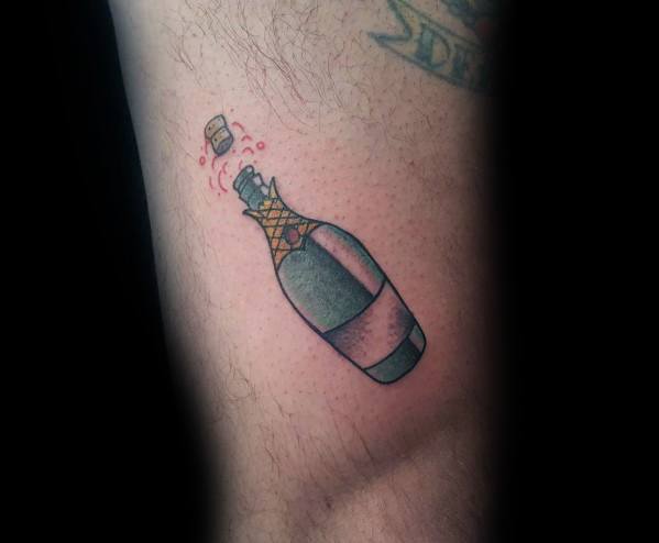 Tattoo of a champagne bottle popping, with bubbles and a cork flying off on a person's skin.
