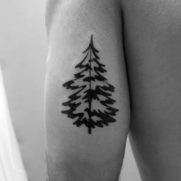 Bold Christmas tree tattoo with a solid black silhouette and sharp, jagged branches, creating a rugged and minimalist design on the arm.