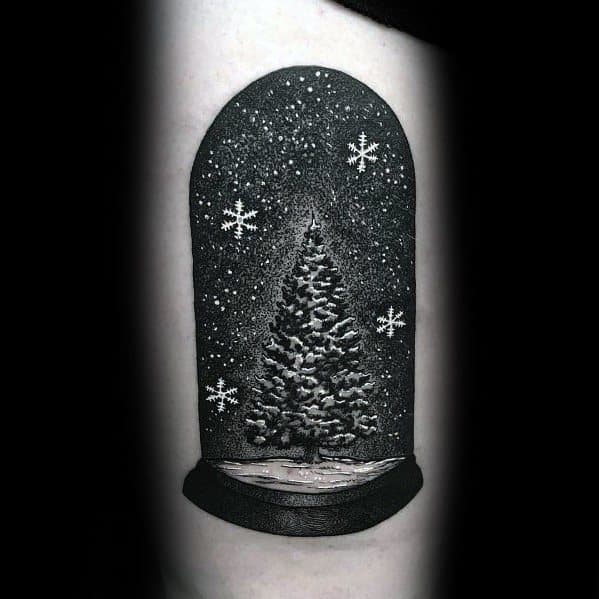 Realistic Christmas tree snow globe tattoo with intricate shading, snowfall details, and glowing snowflakes, creating a festive winter scene.
