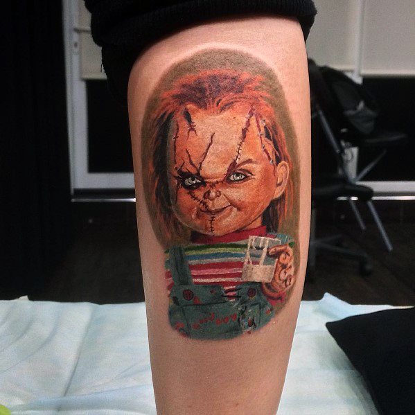 Realistic Chucky tattoo with vivid colors, featuring his stitched face, sinister grin, and detailed shading for a bold horror-inspired design.