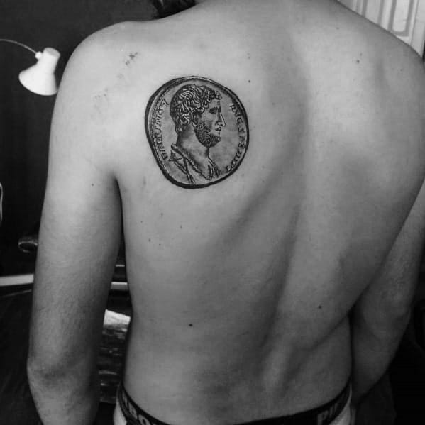 Realistic tattoo of an ancient Roman coin featuring Emperor Marcus Aurelius, placed on the upper back with intricate shading for depth.