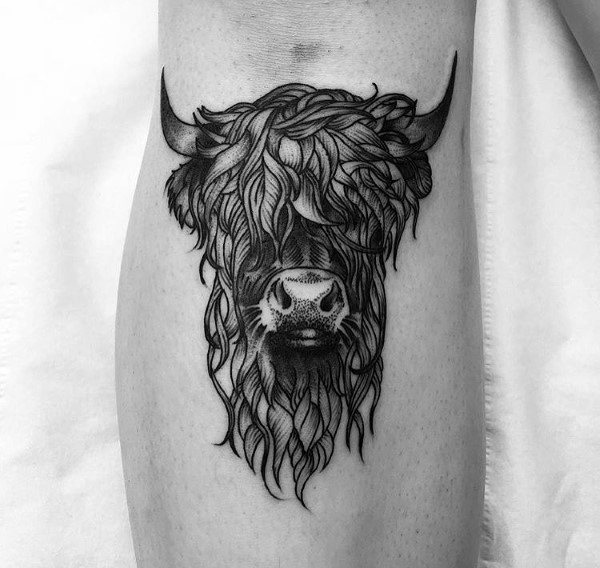Detailed Highland cow head tattoo with flowing, textured fur and bold black lines, centered on the calf for a striking look.