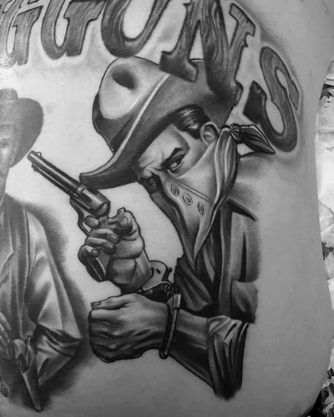 Black and gray tattoo of a masked cowboy holding a revolver, with intense shading and fine details, featuring the word "GUNS" in bold lettering.