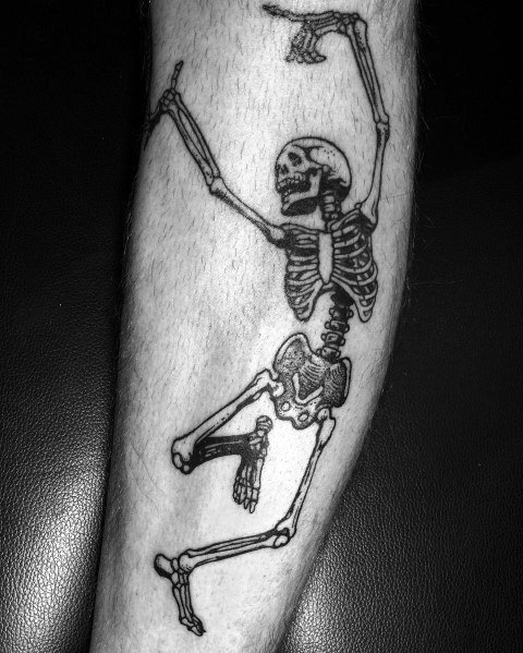 Dancing skeleton tattoo with bold black ink, raised arms, and a lively pose, creating a striking and energetic design on the forearm.