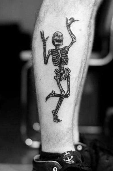 Dancing skeleton tattoo with raised arms and a lively pose, inked in bold black for a striking and energetic design on the calf.