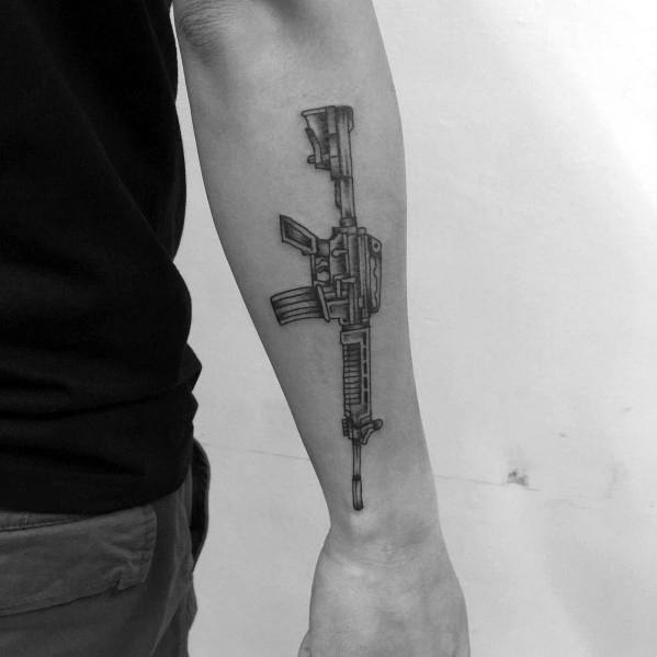 Thin-line AR-15 tattoo on the forearm, featuring a minimalist yet detailed design with a tactical grip and magazine, symbolizing strength and precision.
