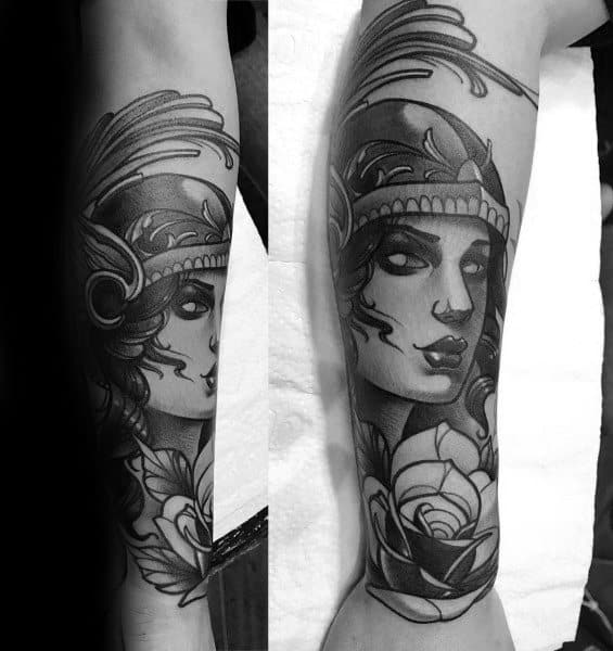 Neo-traditional Athena tattoo on forearm with bold lines, stylized helmet, expressive eyes, and a large rose at the bottom