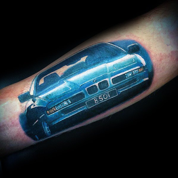 Vibrant BMW 850i tattoo on forearm, featuring a realistic blue design with shading and highlights for a dynamic, 3D effect.