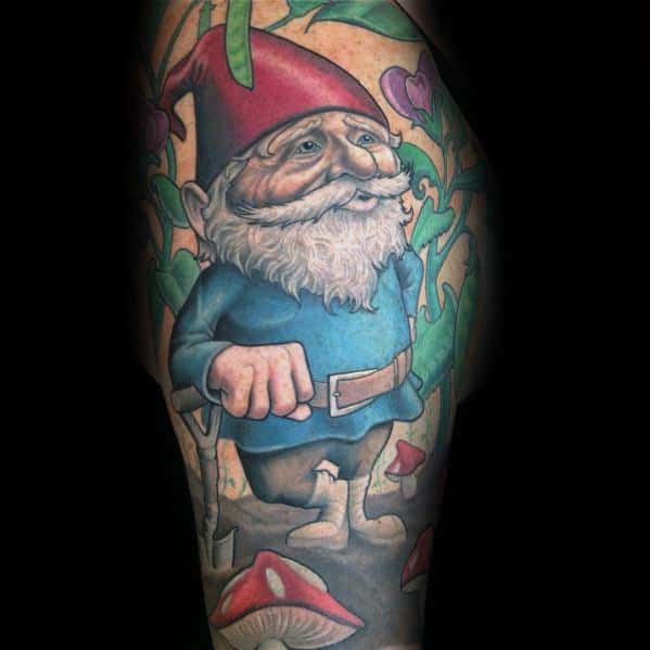 Tattoo of a cheerful gnome with a red hat, white beard, and blue coat, standing among mushrooms and green vines in a fantasy-themed design.