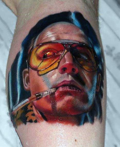 Hyper-realistic Hunter S. Thompson tattoo featuring a vibrant portrait with aviator glasses, a cigarette, and bold shading for a striking 3D effect.