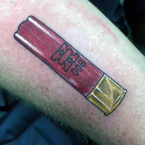 Bold shotgun shell tattoo featuring red and gold tones with fine black outlines, creating a clean and vibrant design.