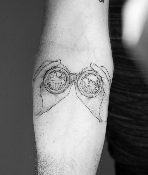 Fine-line tattoo of hands holding binoculars with globes in the lenses, symbolizing exploration, travel, and a global perspective.