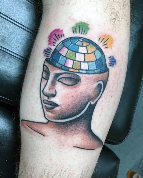 Unique tattoo of a serene face with a disco ball brain, radiating colorful lights, symbolizing creativity, music, and a vibrant mindset.