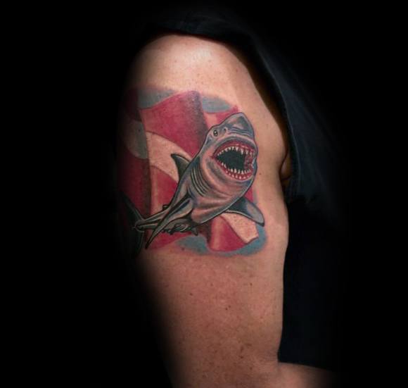 Tattoo of a fierce great white shark emerging from a red and white dive flag, representing strength, adventure, and a love for the ocean.
