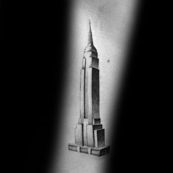 Minimalist Empire State Building tattoo featuring clean lines and subtle dot shading, inked elegantly on a man's skin.