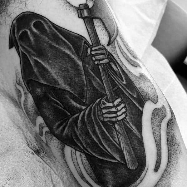 Dark executioner tattoo in black and grey, featuring a hooded figure gripping a large axe, with skeletal hands and flowing cloak details.