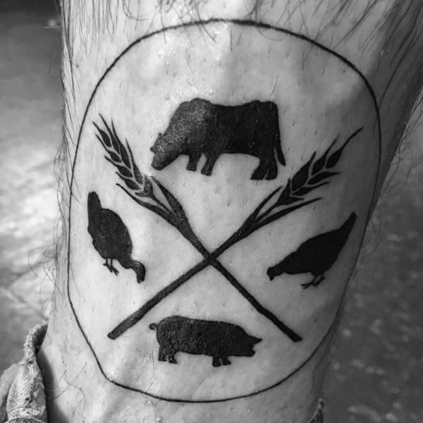 Bold black tattoo of farm animal silhouettes—cow, pig, and chickens—framed by crossed wheat stalks inside an oval outline.