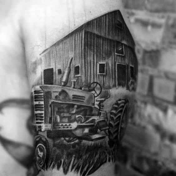 Detailed black and gray tattoo of a vintage tractor in front of a large barn, capturing a classic rural farm scene.