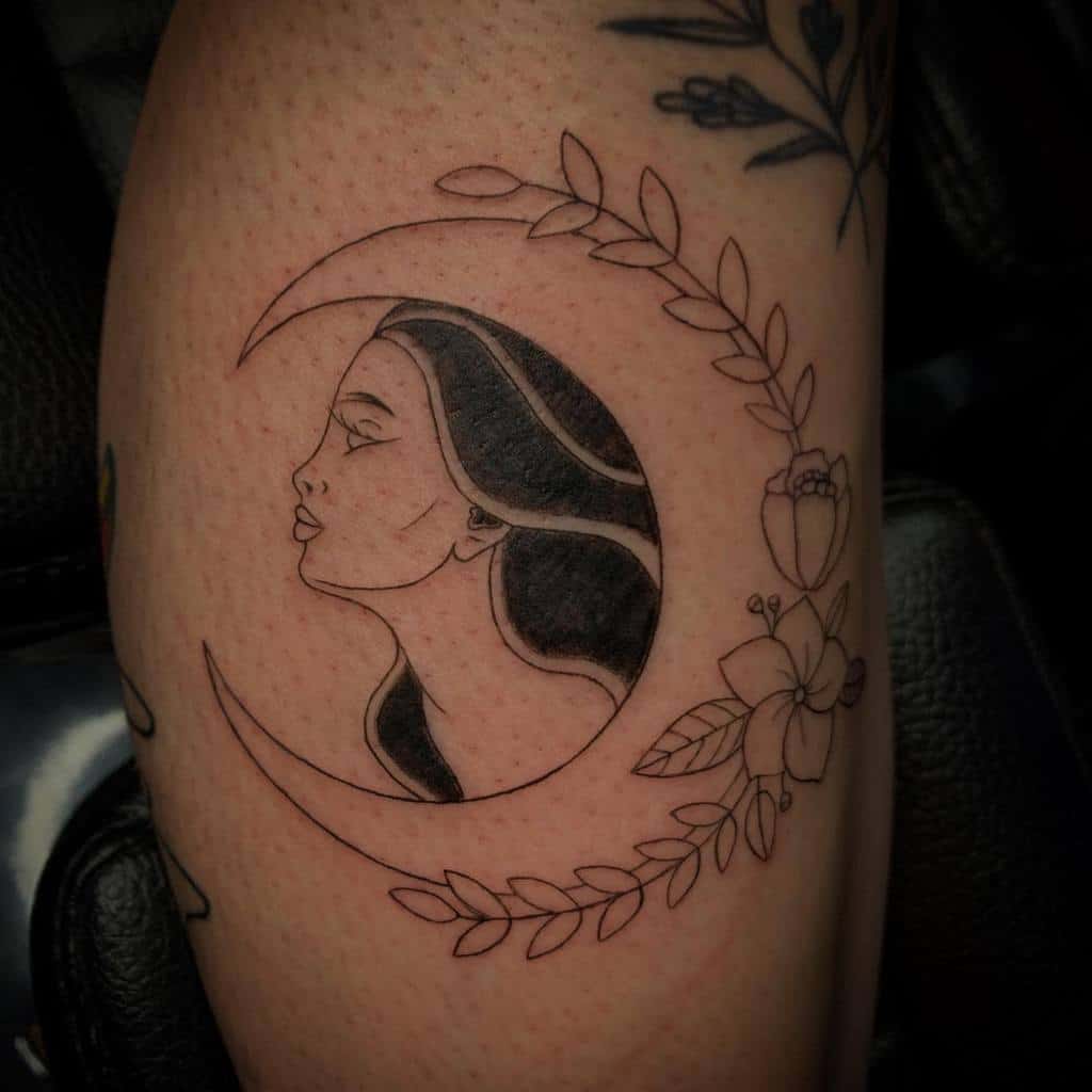 Tattoo of a woman's profile within a crescent moon, surrounded by roses and leaves