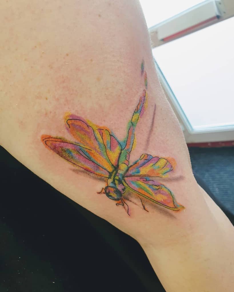 Colorful dragonfly tattoo, featuring vivid shades of blue, green, and orange in a realistic style