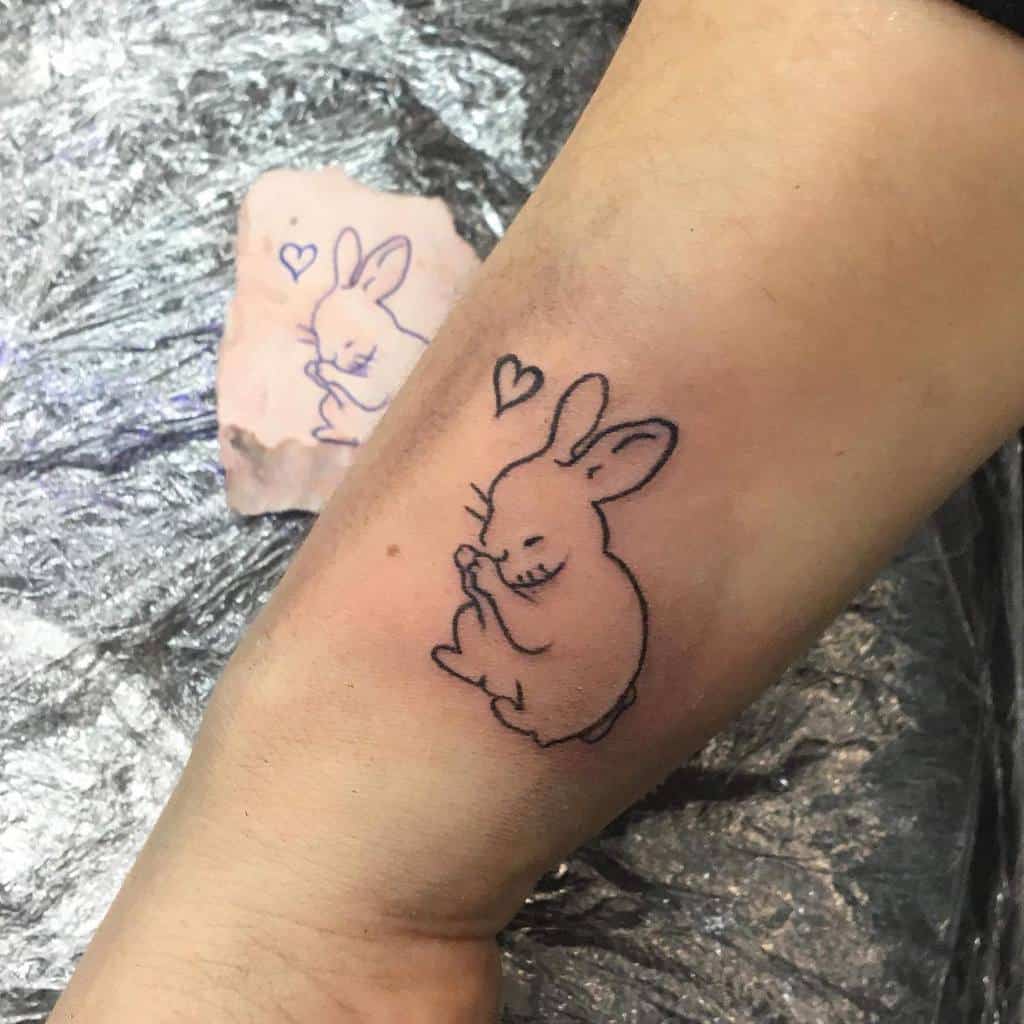 Tattoo of a smiling bunny with hearts above its head