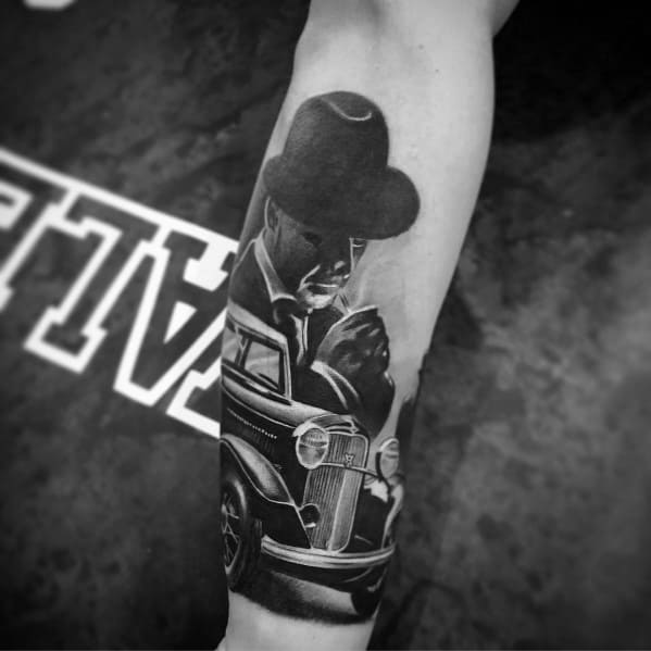 Realistic black and grey tattoo featuring a vintage Ford car and a mysterious man in a fedora, creating a classic gangster-era aesthetic.