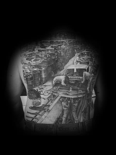 Realistic black and grey full-back tattoo depicting a historic Ford assembly line, featuring workers building classic cars with intricate detailing.