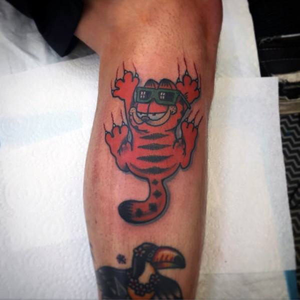 Garfield tattoo clawing down with a grin, wearing sunglasses—bold and dynamic design with a cool, playful attitude.