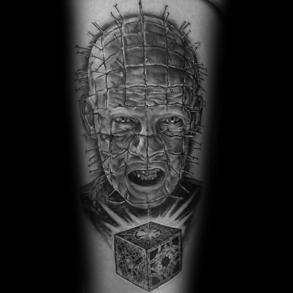 Black and grey *Hellraiser* tattoo of Pinhead with intense shading, intricate pin details, and a glowing Lament Configuration for a haunting effect.