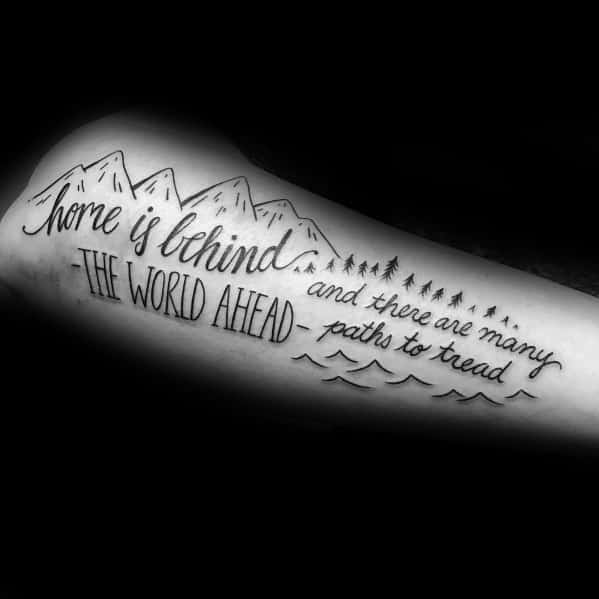 Mountain-themed tattoo with the quote 'Home is behind, the world ahead, and there are many paths to tread,' symbolizing adventure and journey.