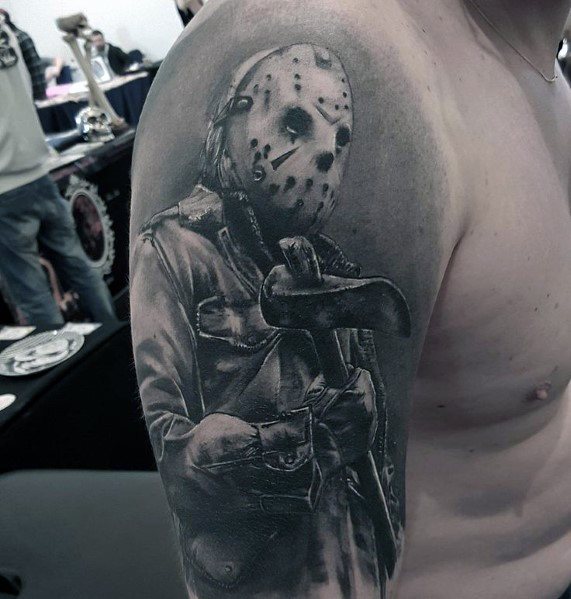 Black and grey tattoo of Jason Voorhees from *Friday the 13th*, featuring his iconic hockey mask and a large axe for a menacing horror look.
