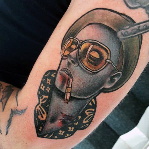 Stylized Hunter S. Thompson tattoo featuring a monochromatic portrait with aviator glasses, a cigarette, and a patterned collar, blending realism with bold outlines.