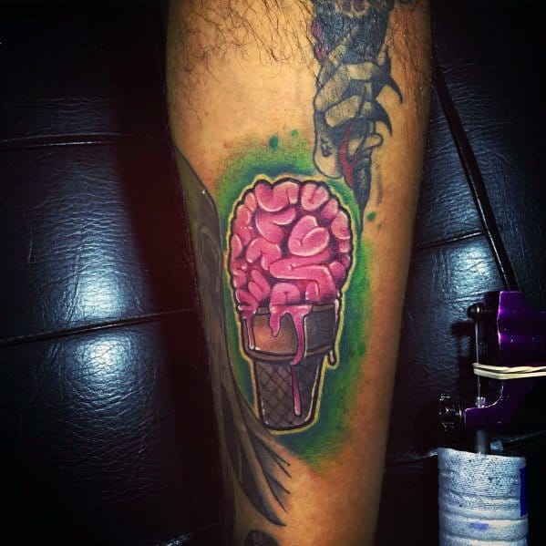 Tattoo of a melting pink brain in an ice cream cone, featuring bold outlines, vibrant shading, and a green glow for a surreal and horror-inspired design.